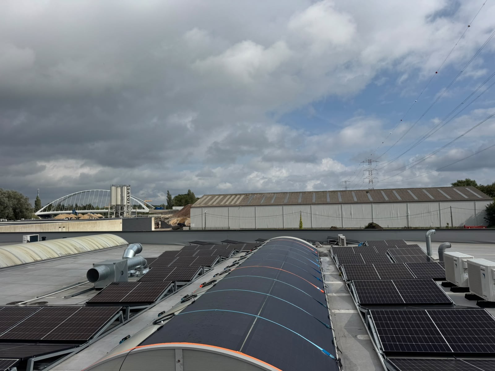 Wider view of the factory roof showing the covered curved bay and a second uncovered arched bay alongside