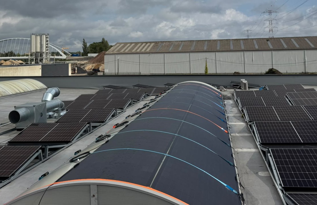 Close view of flexible solar modules following the curve of the roof with MC4 cable runs along both sides