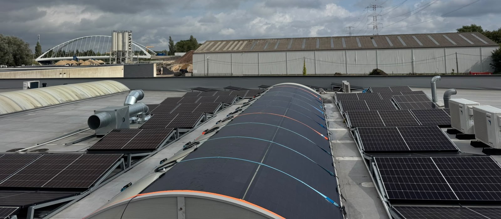 The curved flexible array meeting the rigid modules on tilt frames on the flat roof either side