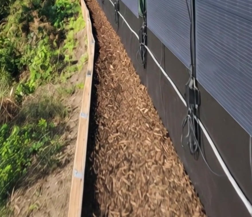 MC4 output cables from vertical flexible solar panels running along the bottom of a garden fence